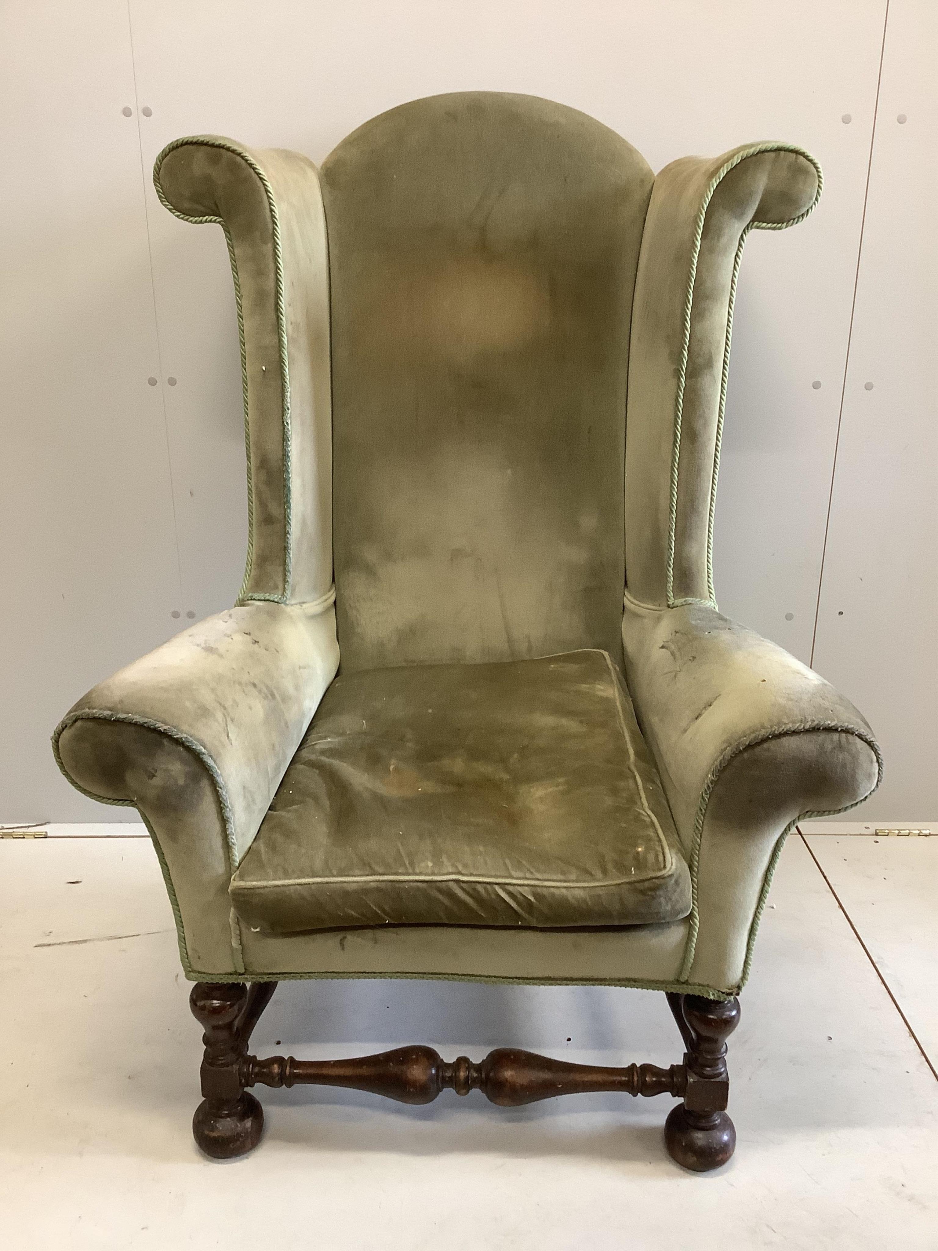 A William and Mary style wing back armchair, upholstered in green dralon, width 68cm, height 136cm. Condition - poor
